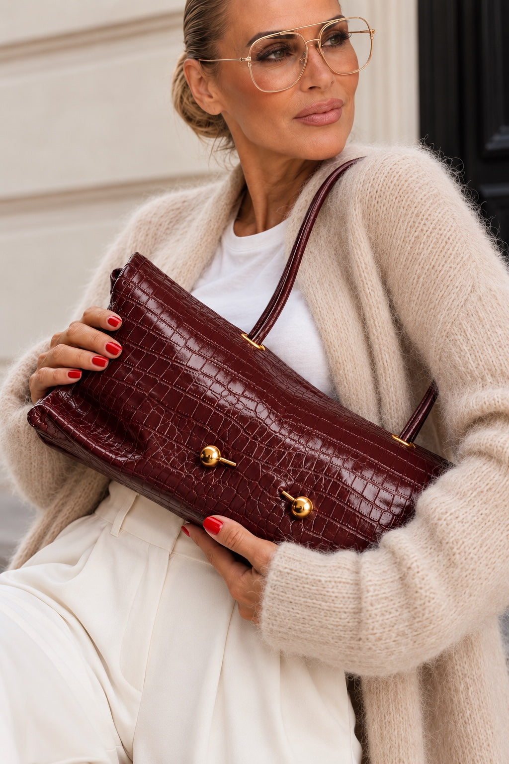 Model mit THE CROCO ICON in Burgunderrot und cremefarbenem Strick