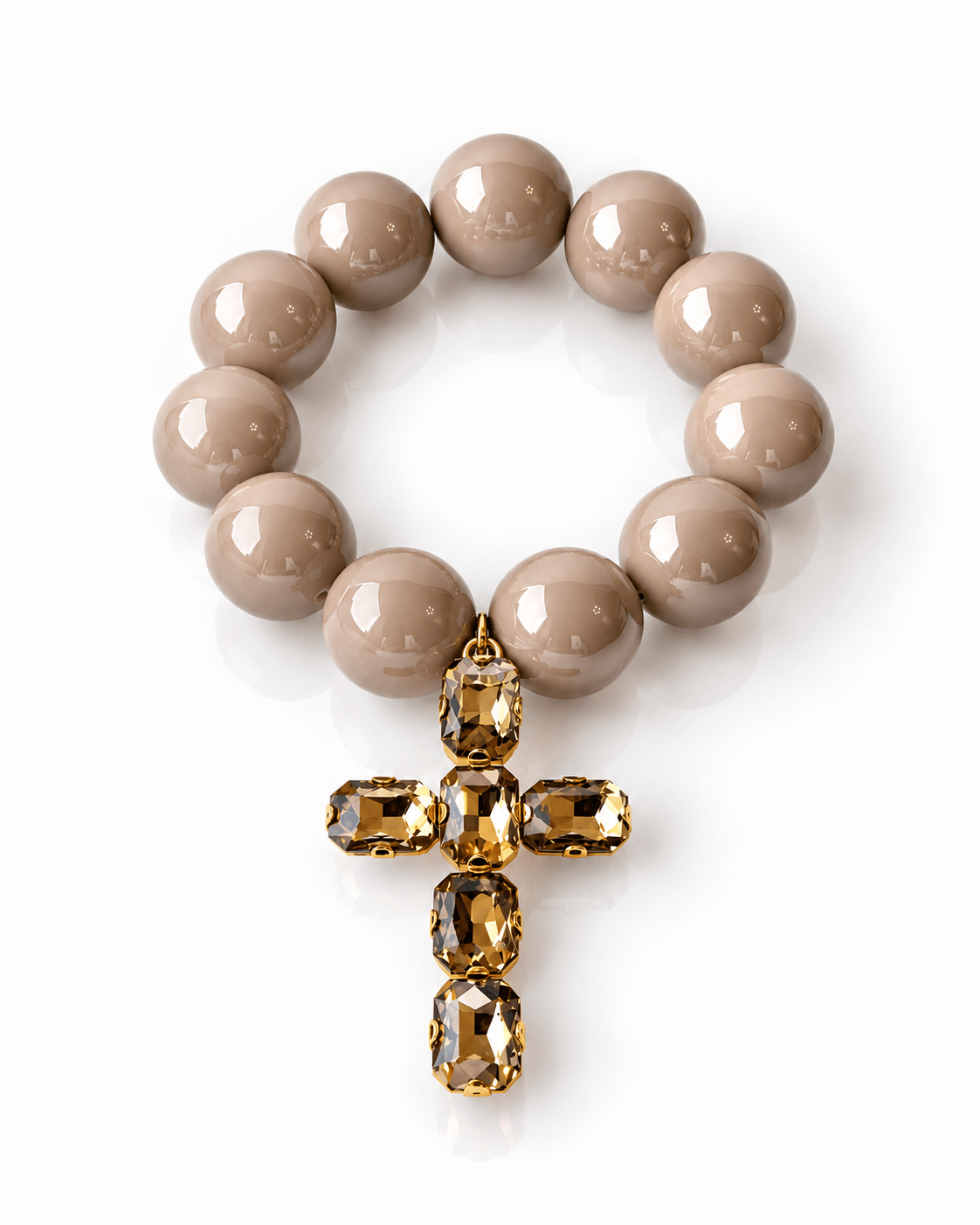 The Grand Cross Armband mit großen glänzenden Resin-Perlen in warmem Beige und Kreuzanhänger mit facettierten Kristallsteinen in Creme.