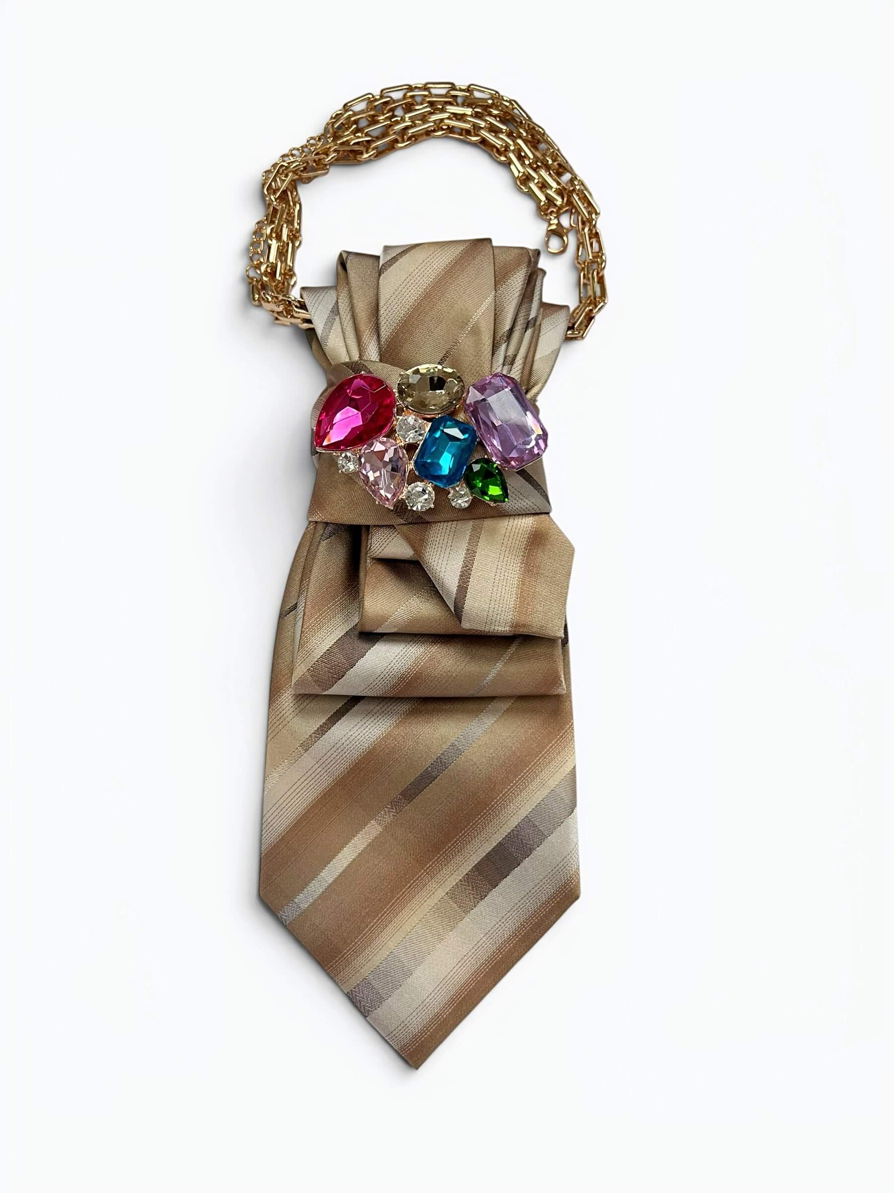 Vintage-Krawatte in Champagner, Beige und Taupe mit diagonalem Streifenmuster, dekorativer Schmuckbrosche mit bunten Steinen und goldfarbener Kette.