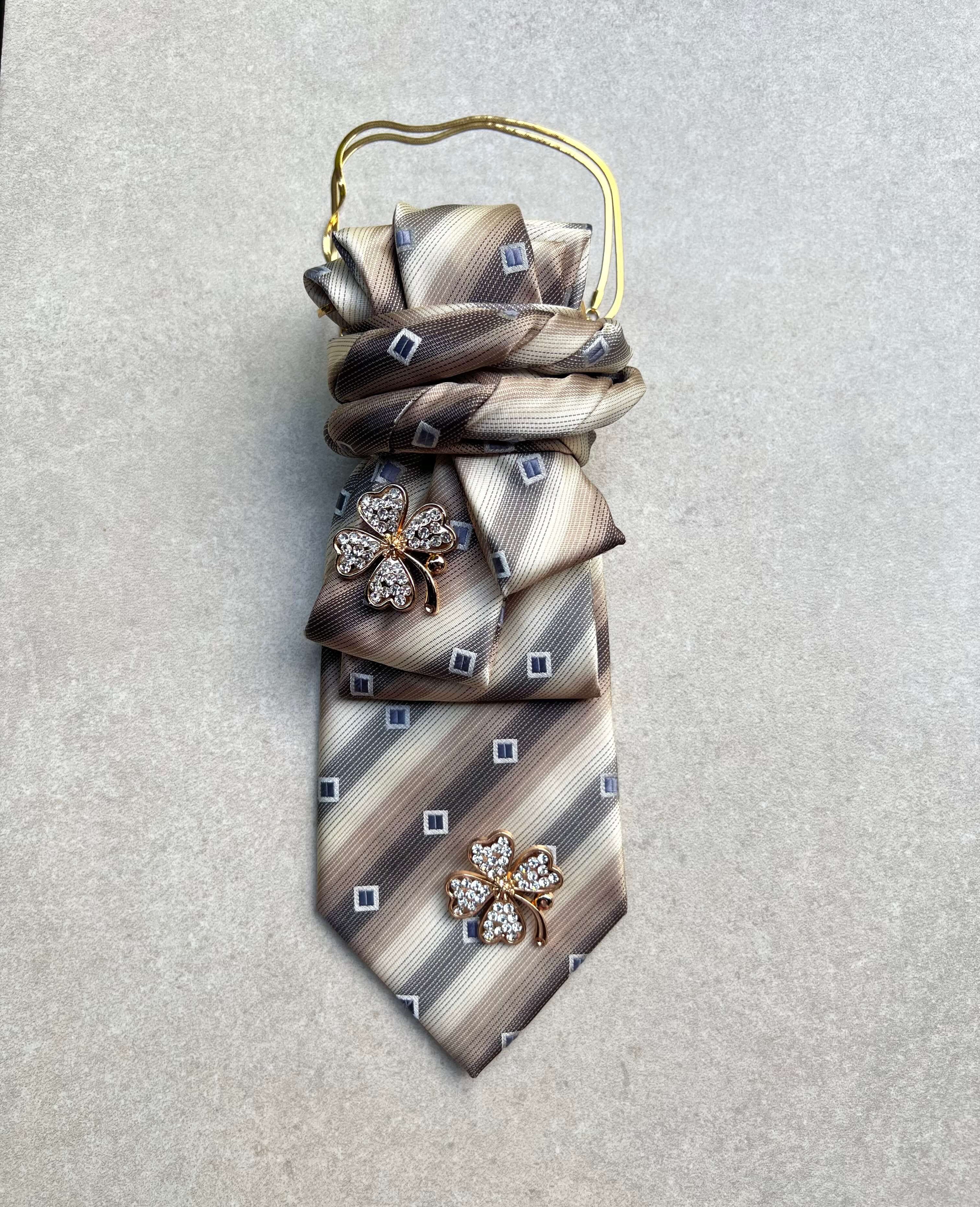 Vintage-Krawatte in Beige-, Taupe- und Grautönen mit geometrischem Muster, goldfarbener Kette und zwei Kleeblattbroschen mit klaren Kristallsteinen. 